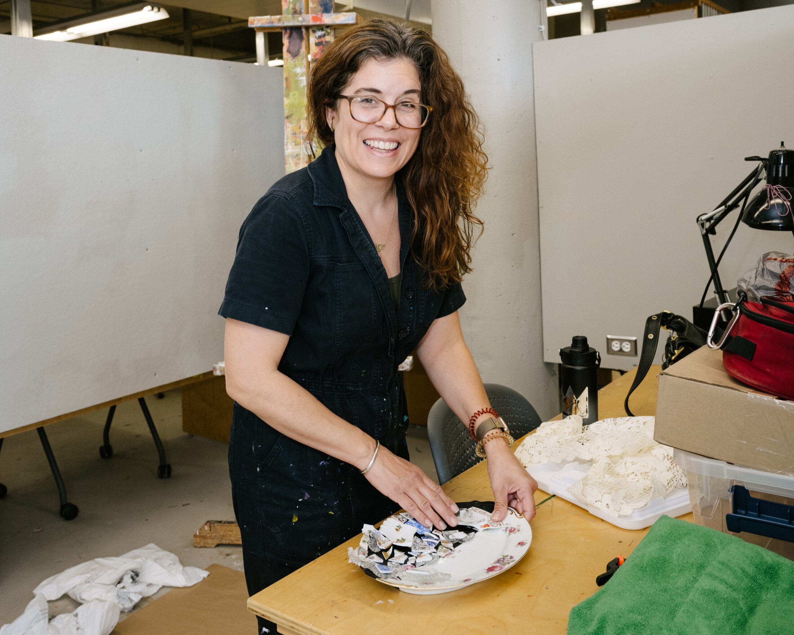 A figure in protective equipment pours molten metal into a mold.